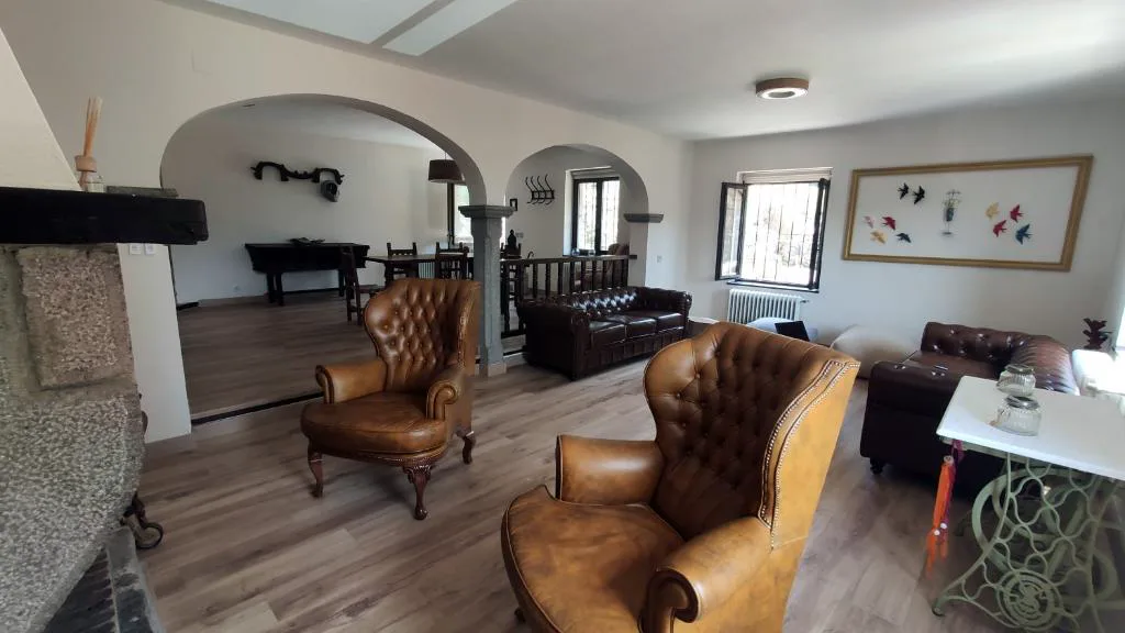 Salón con sofás de cuero, chimenea y arcos de piedra