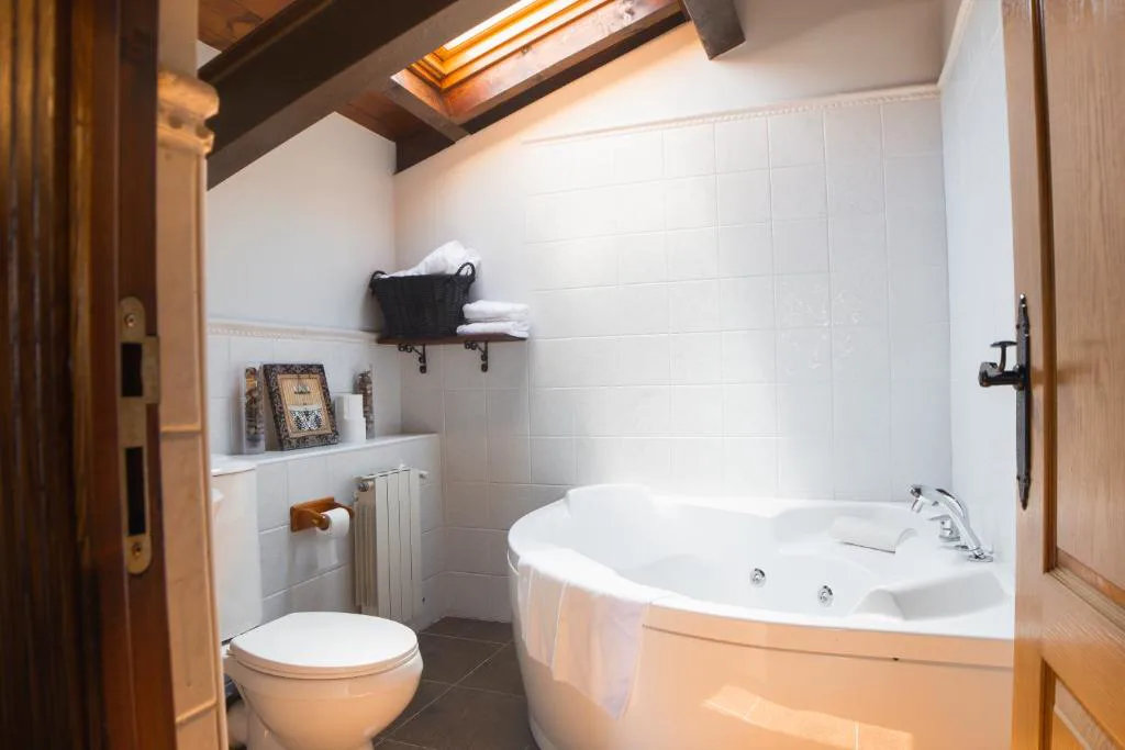 Baño con bañera de hidromasaje de esquina y muros de madera