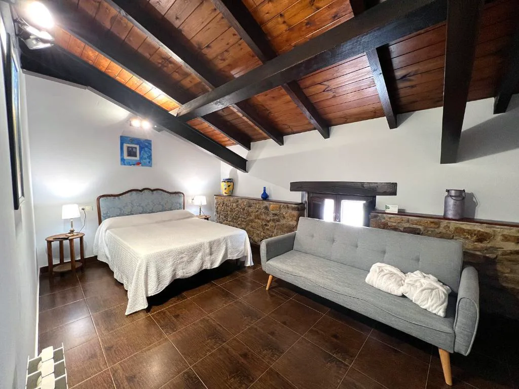 Habitación con vigas, sofá cama y cabecero azul