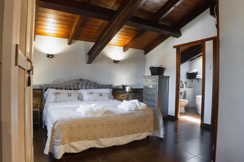 Habitación con cama doble y baño anexo bajo vigas