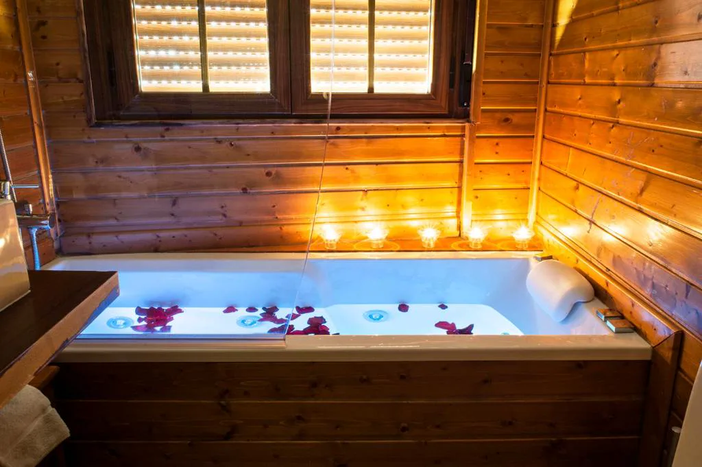 Jacuzzi de madera con velas en una habitación con vigas