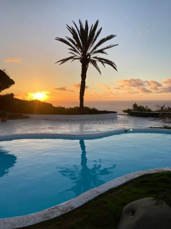 Piscina con palmera silueteada al atardecer y vistas al Atlántico, La Rayuela Suites Boutique, La Frontera, El Hierro