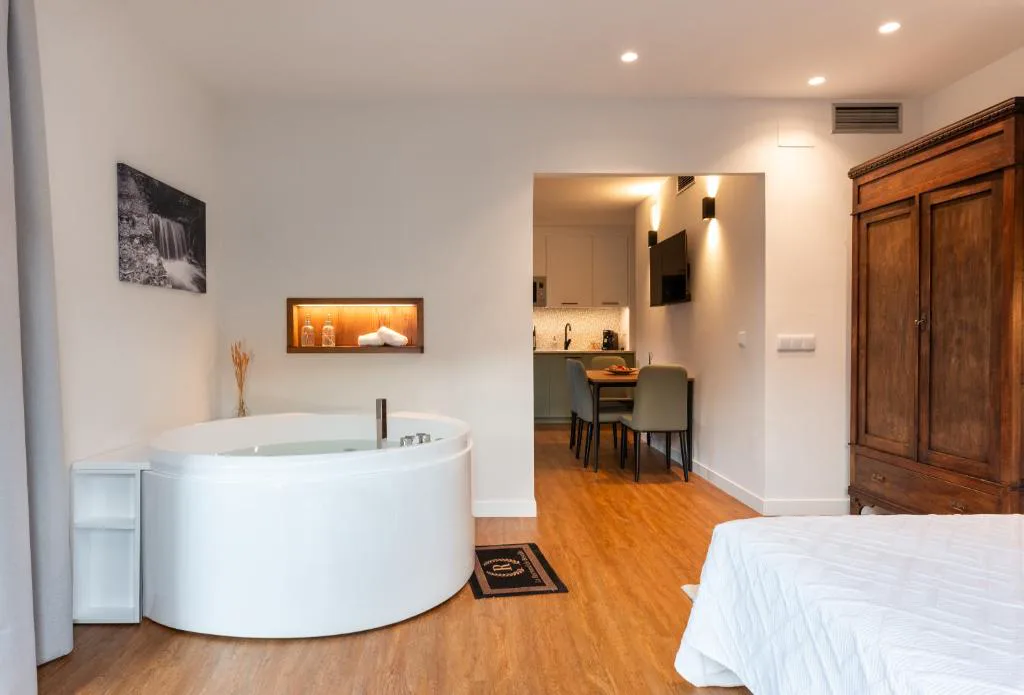 Bañera redonda de hidromasaje junto a la cama y una cocina pequeña