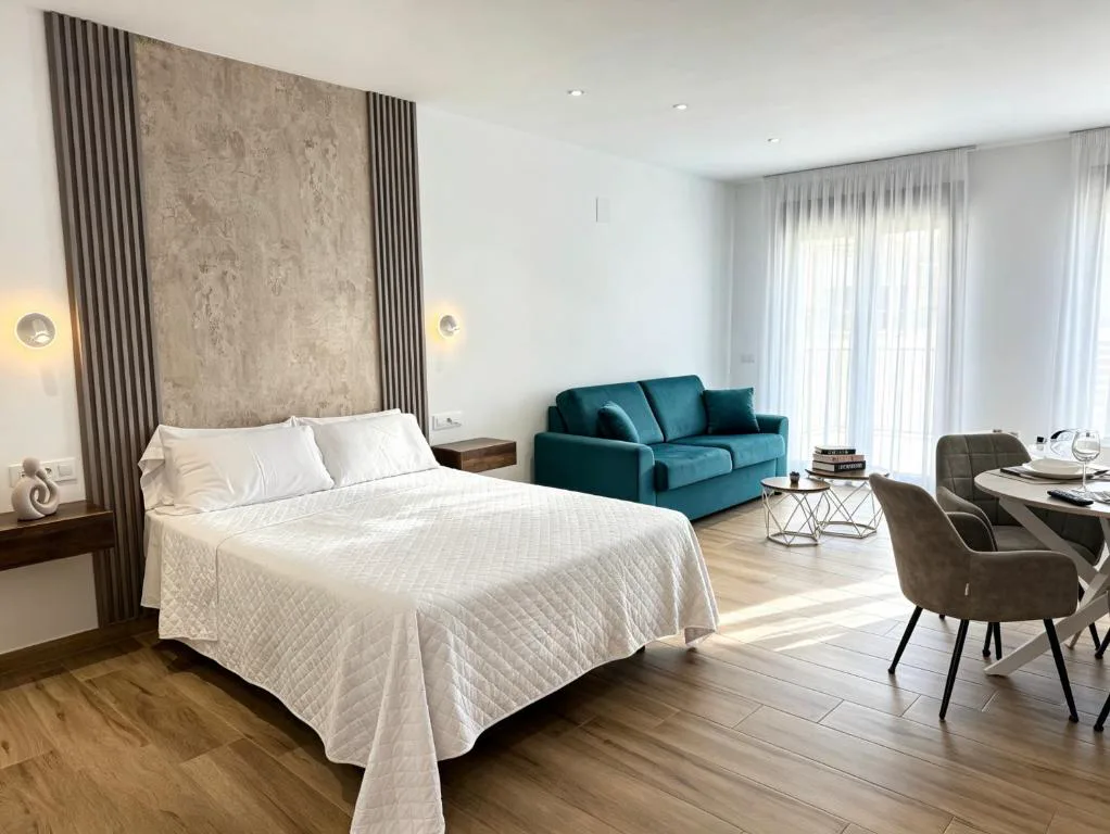 Suite blanca con sofá verde y cama grande