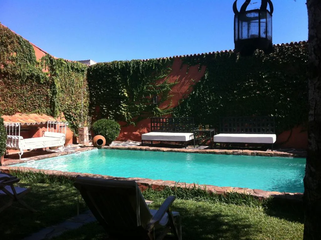 Piscina rodeada de muros con hiedra en un patio
