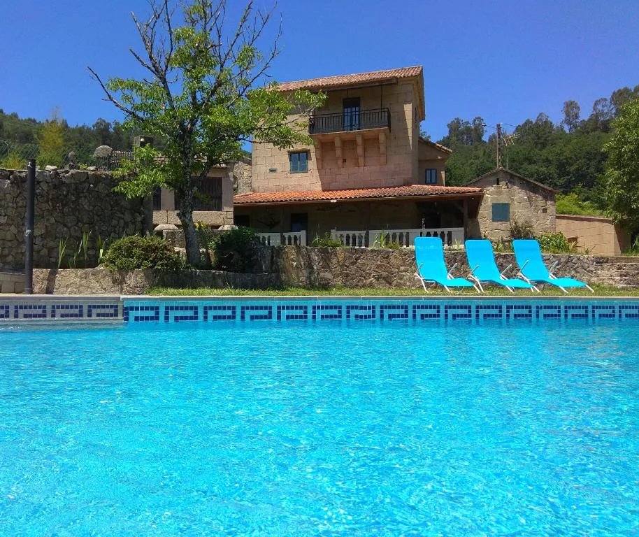 Vista de la piscina privada con tumbonas azules y la fachada de piedra al fondo, La Torre Mondariz