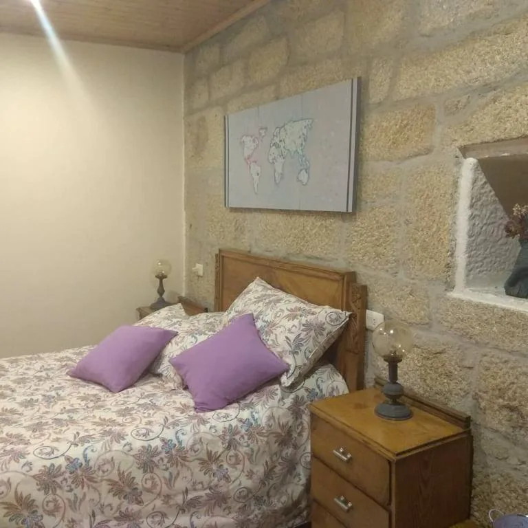 Habitación con paredes de piedra vista y ropa de cama estampada, La Torre Mondariz