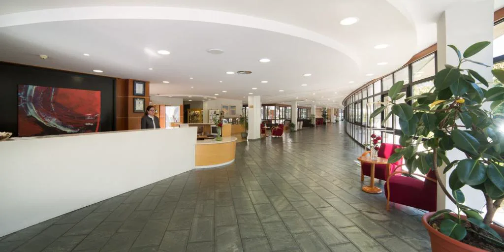Recepción y pasillo elegante del balneario con sillones rojos, Laias Caldaria