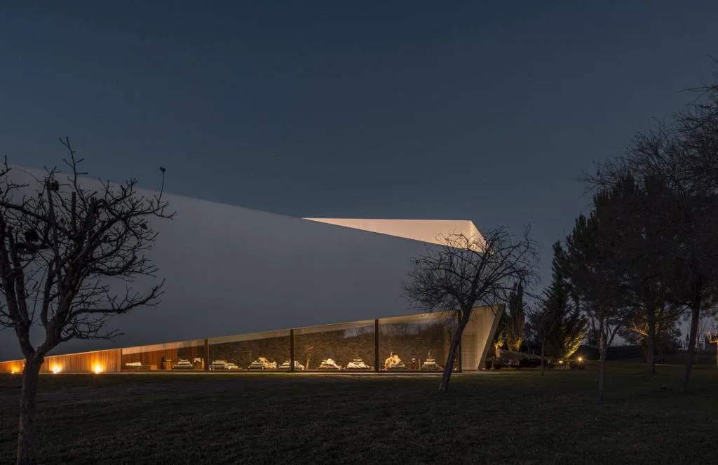Vista nocturna de la arquitectura angular en piedra del hotel L'AND Vineyards