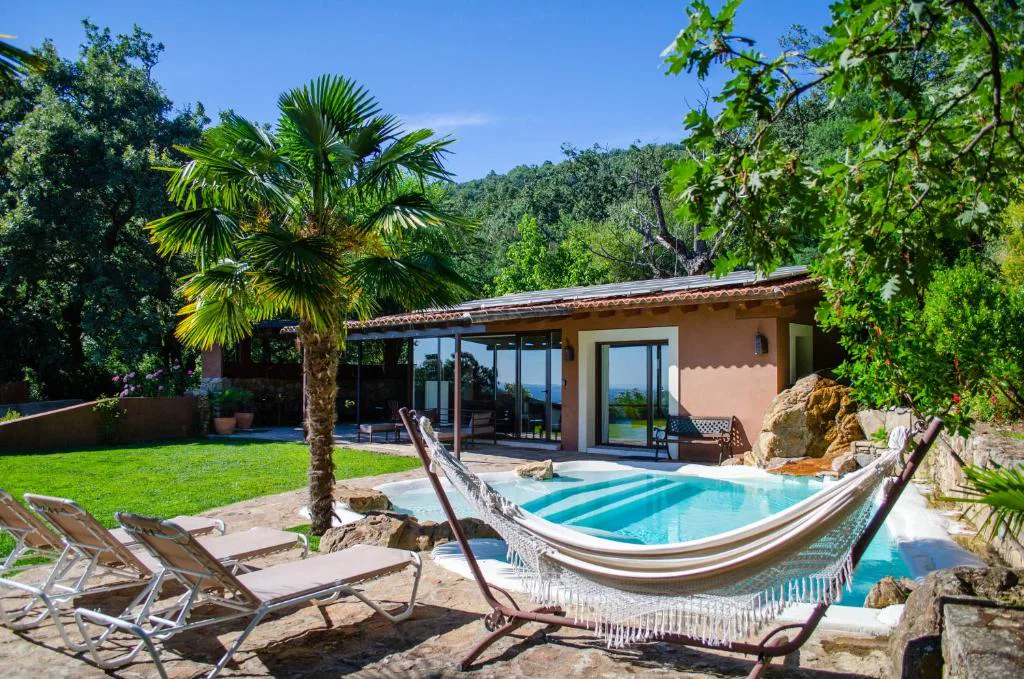 Piscina con hamaca colgada y tumbonas junto a la villa