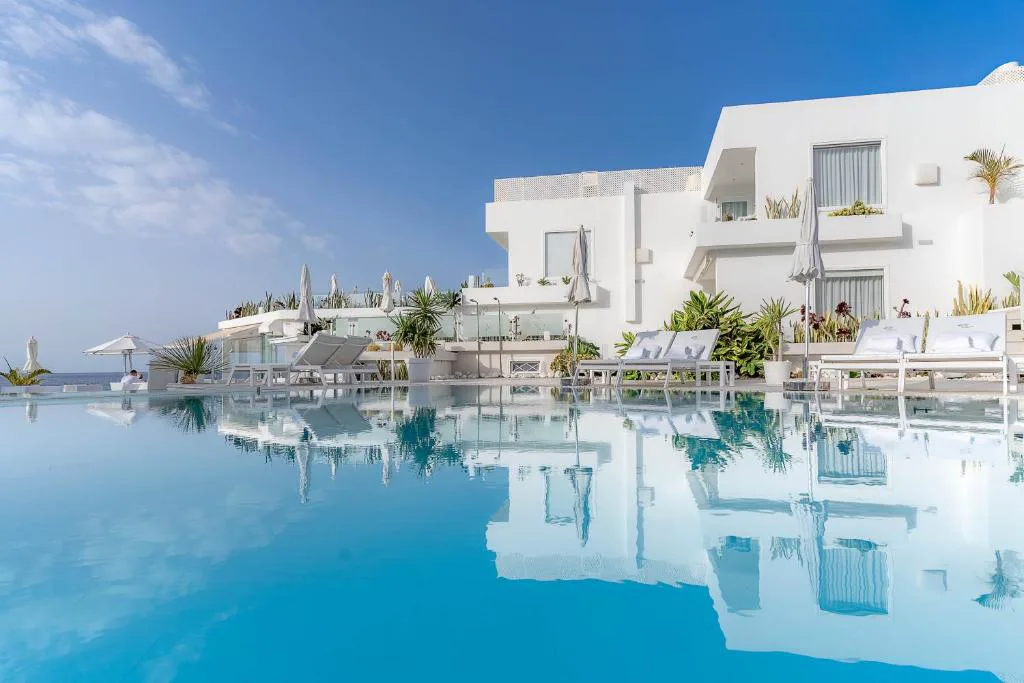 Piscina exterior reflejando las villas blancas de arquitectura ibicenca, Lani's Suites de Luxe