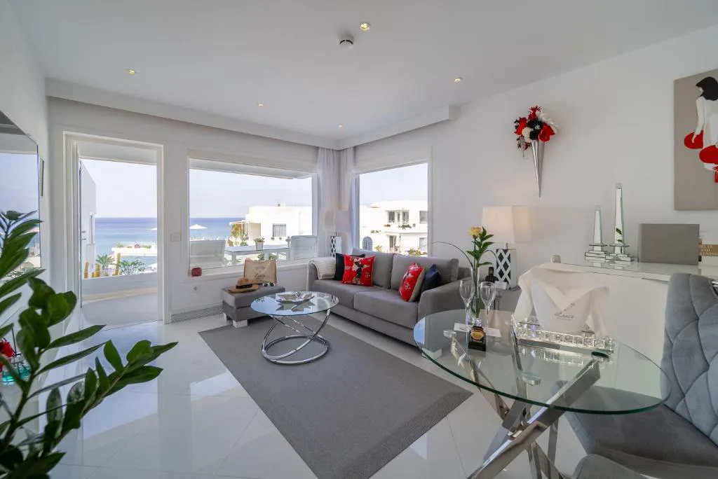 Salón de la suite con sofá gris y vistas al mar desde el balcón, Lani's Suites de Luxe