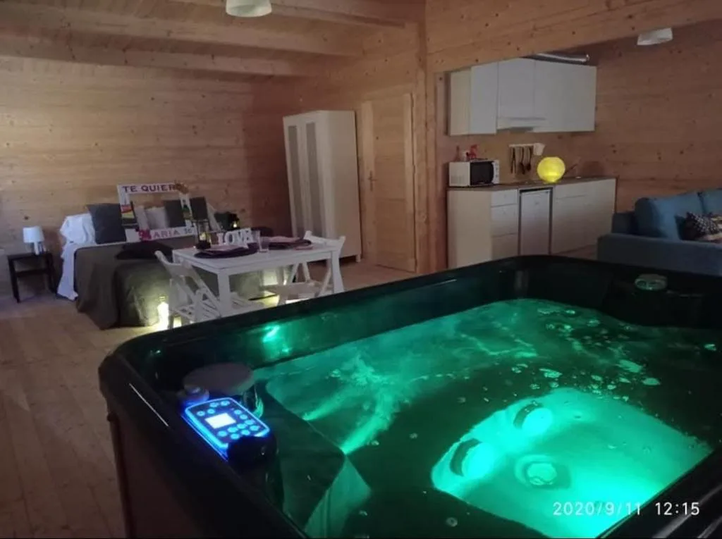 Jacuzzi con luz verde junto a una cama de madera
