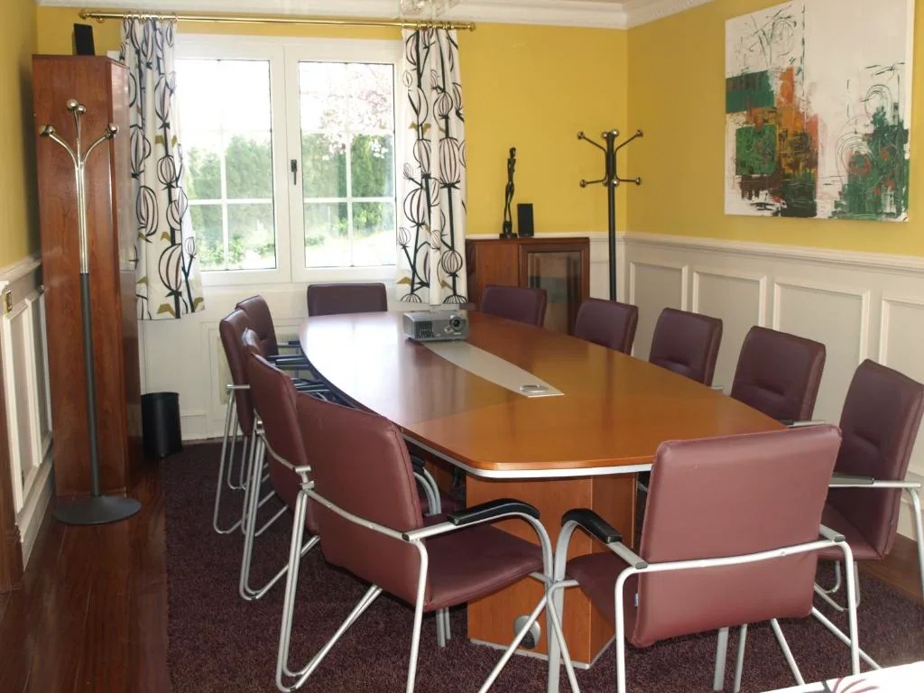 Sala de reuniones con mesa larga y sillas granates