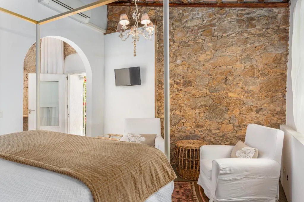 Habitación blanca con pared de piedra y cama doble