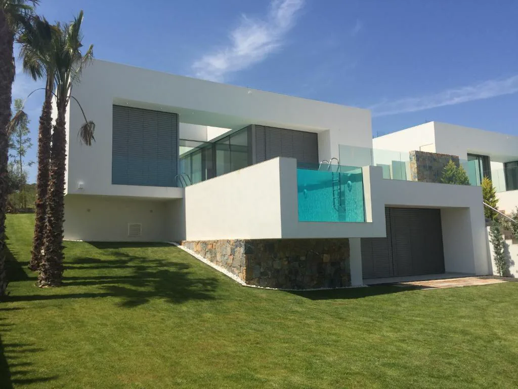Fachada blanca de la villa con balcón de cristal