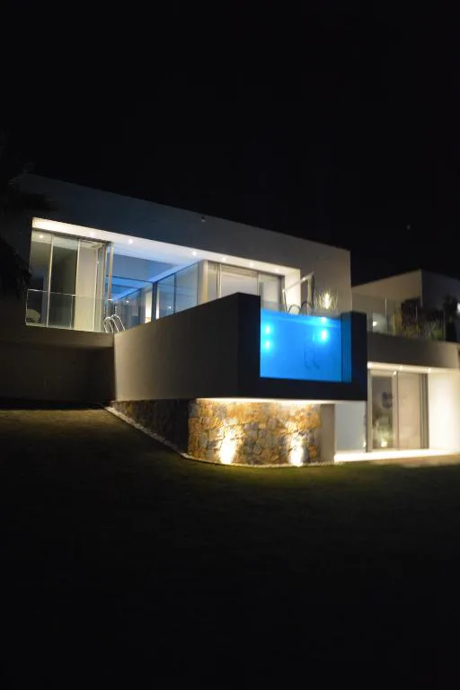Villa iluminada de noche con la piscina encendida