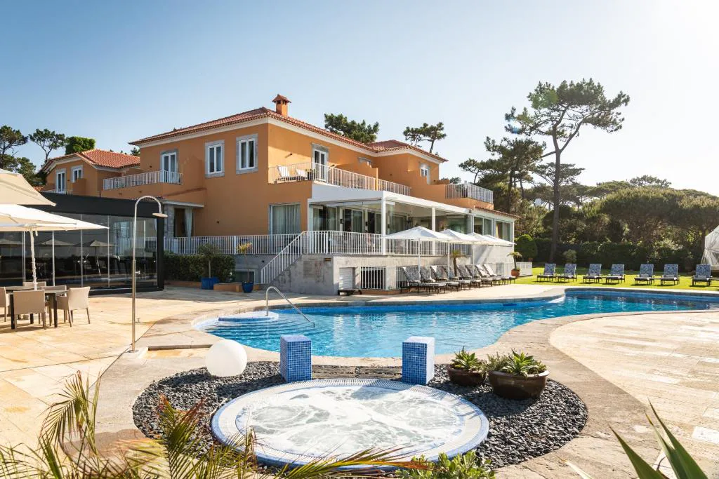 Piscina y jacuzzi frente al palacete color mostaza de Longevity Senses, Cascais