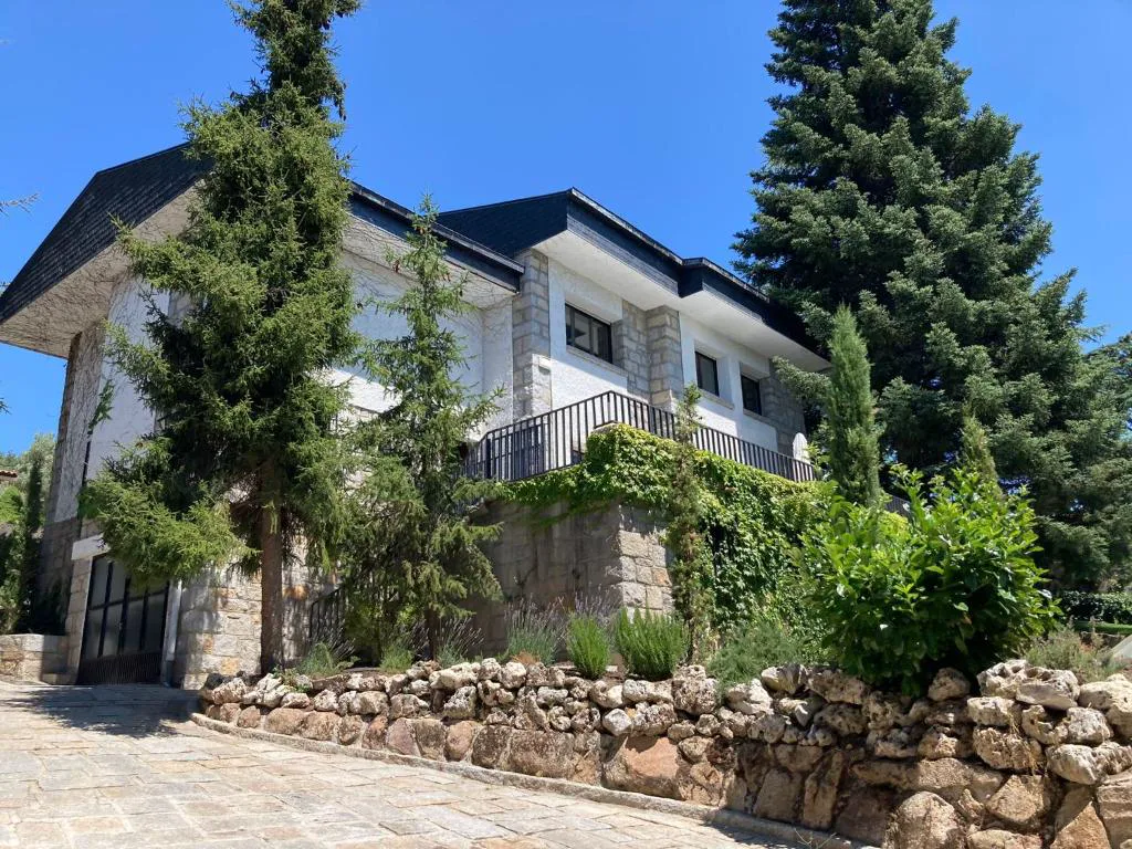 Casa de piedra y ladrillo entre setos y árboles del jardín