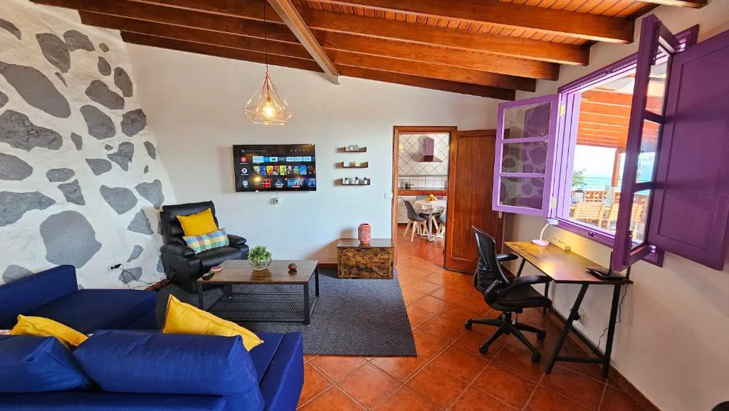 Salón con sofá azul, sillón de cuero y ventana morada abierta al mar, Los Cerrajones