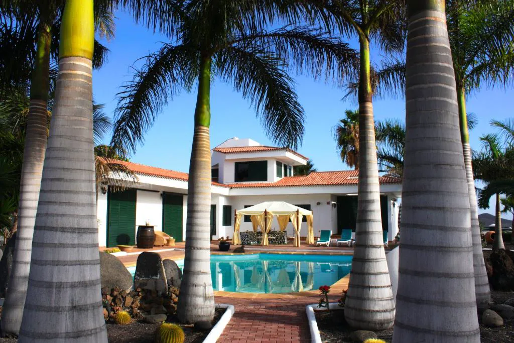 Piscina enmarcada por palmeras con la villa blanca al fondo, Los Fondos