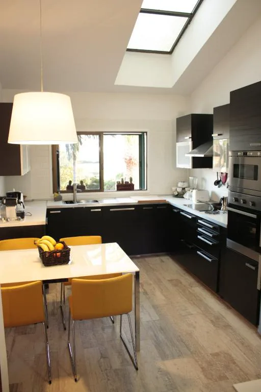 Cocina moderna en tonos oscuros con isla y sillas amarillas, Los Fondos