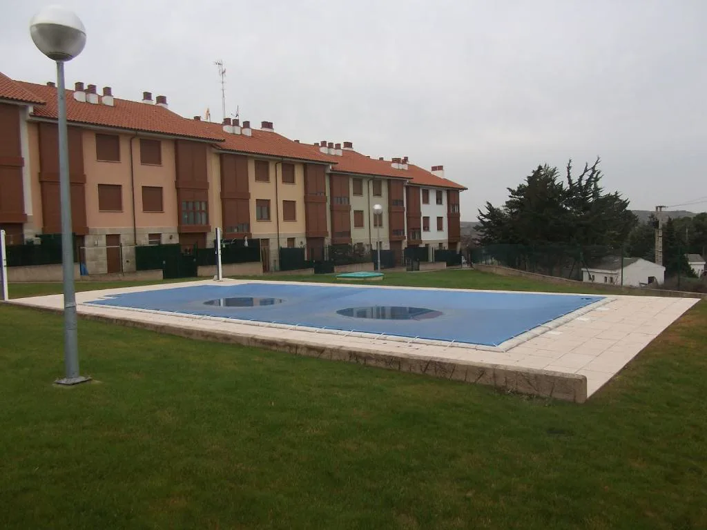 Piscina azul entre césped y bloques de apartamentos