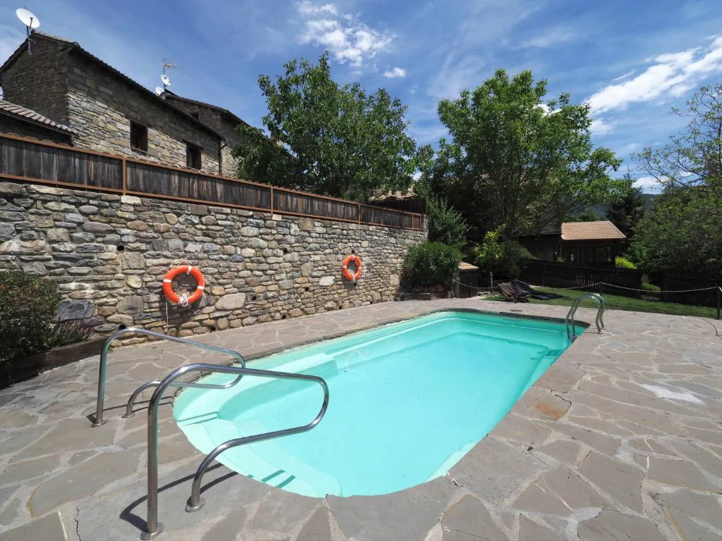 Piscina con forma libre junto a un muro de piedra