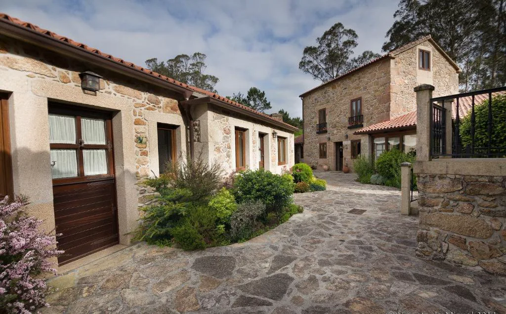 Conjunto de casas de piedra restauradas con patio empedrado y flores, Lugar do Cotariño