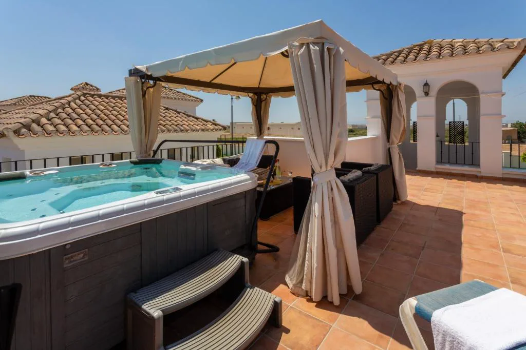 Jacuzzi en la terraza bajo una pérgola con cortinas