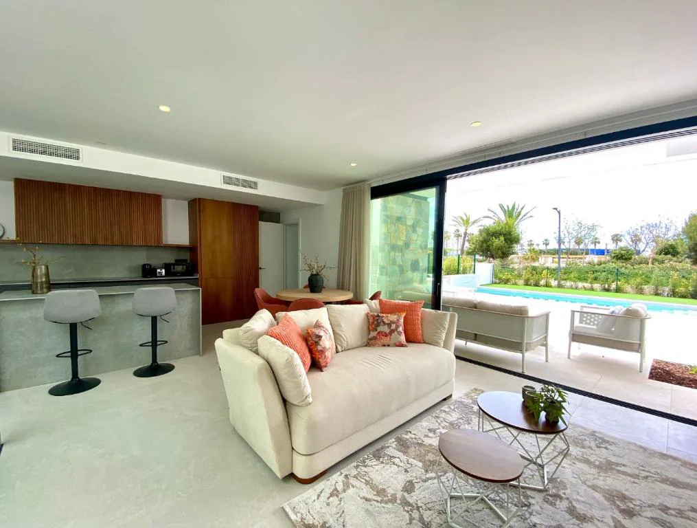 Salón con sofá blanco y cocina abierta
