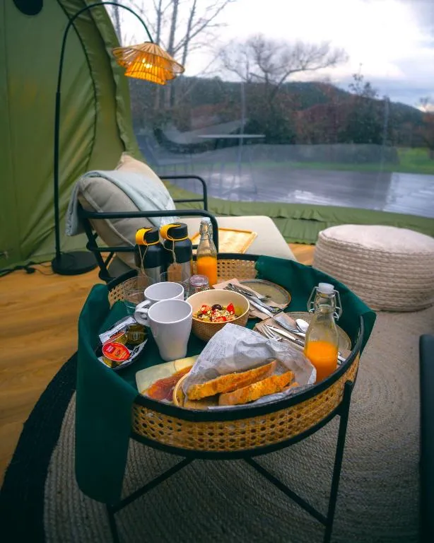 Desayuno servido en bandeja dentro de la burbuja de Luzada Glamping, con vistas al jardín
