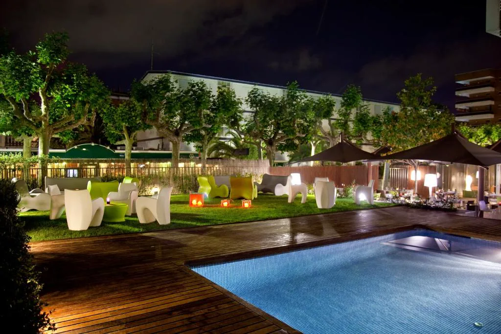 Piscina iluminada por la noche entre jardines