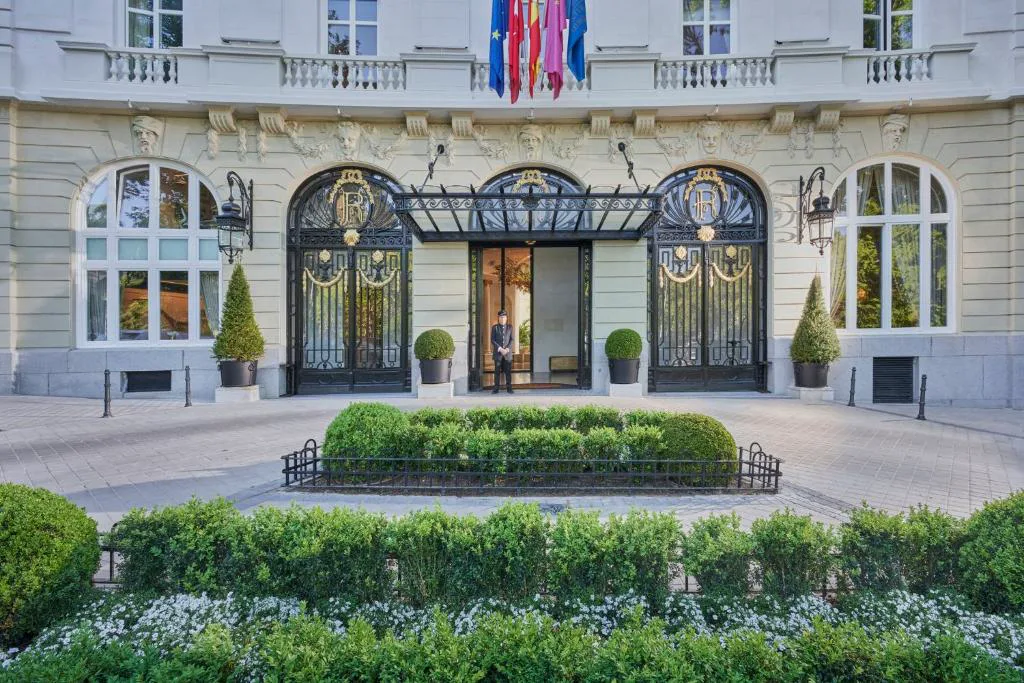 Fachada clásica del hotel con jardín geométrico de setos en primer plano