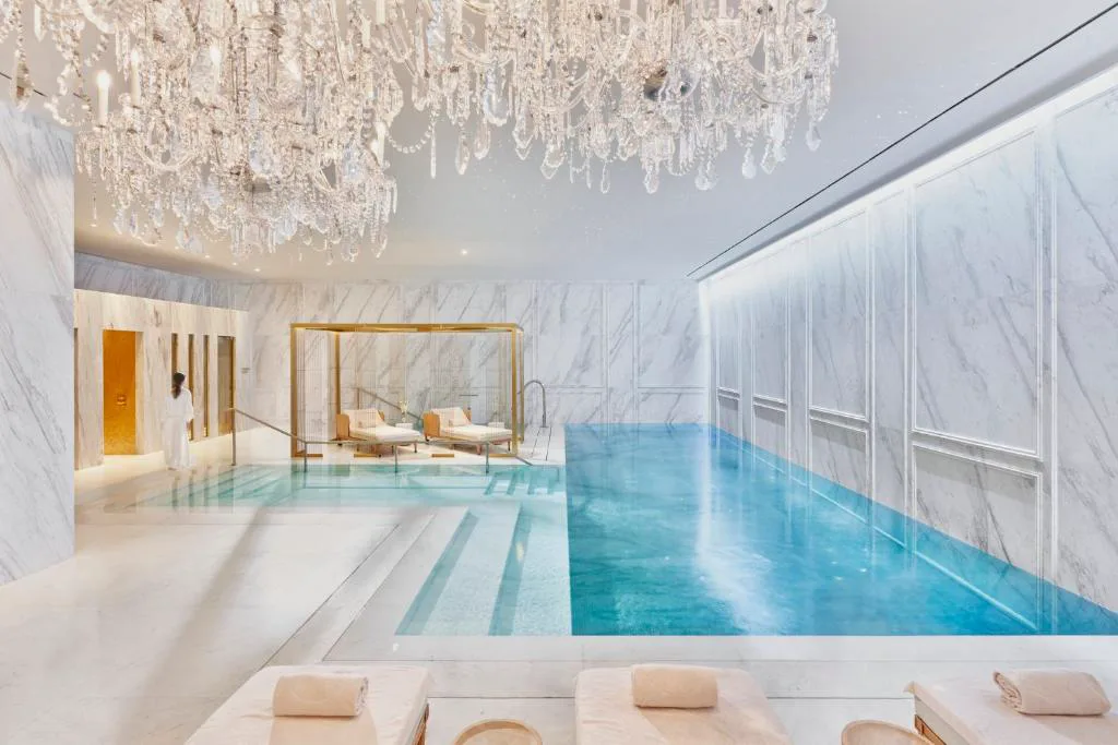 Piscina cubierta de mármol claro con lámparas de cristal