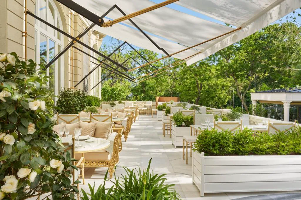 Terraza acristalada con jardín y mesas de restaurante