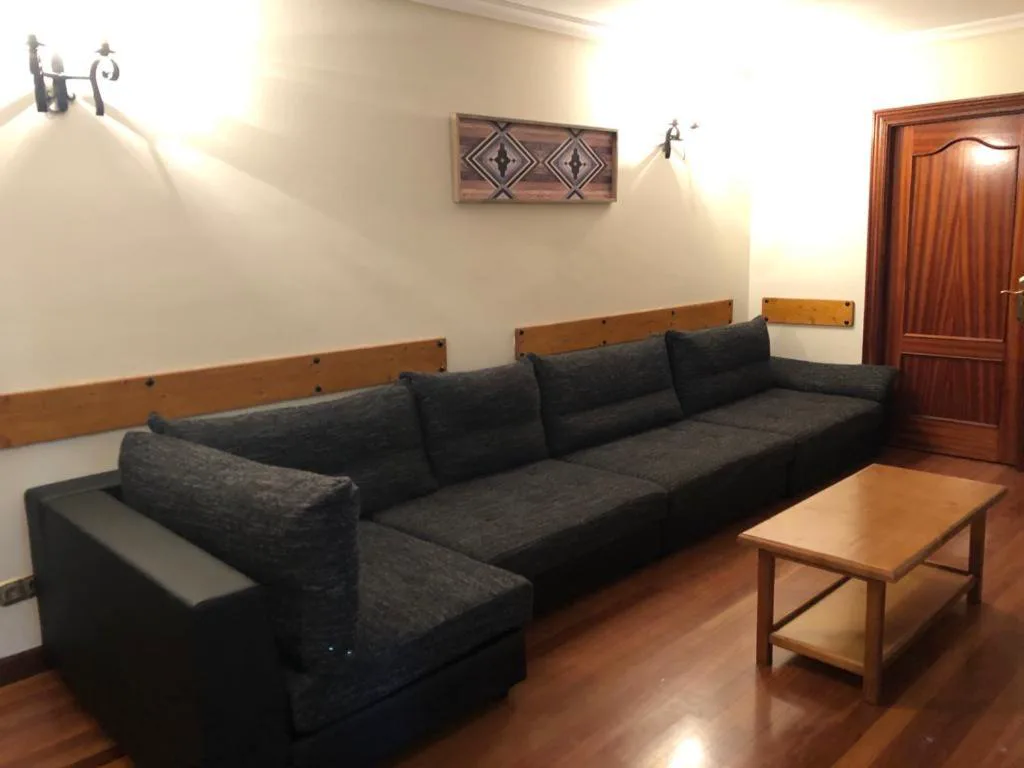Salón con sofás negros y mesa de madera