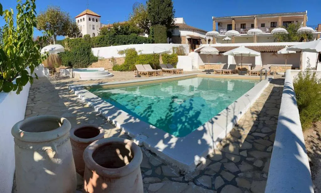 Piscina rectangular entre casas blancas y tinajas de barro