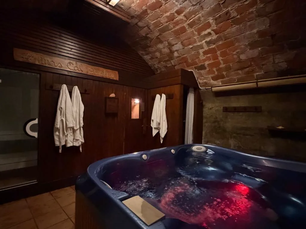 Sala con jacuzzi iluminado de rojo y albornoces