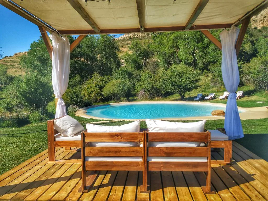 Cenador de madera con sofá de exterior junto a la piscina