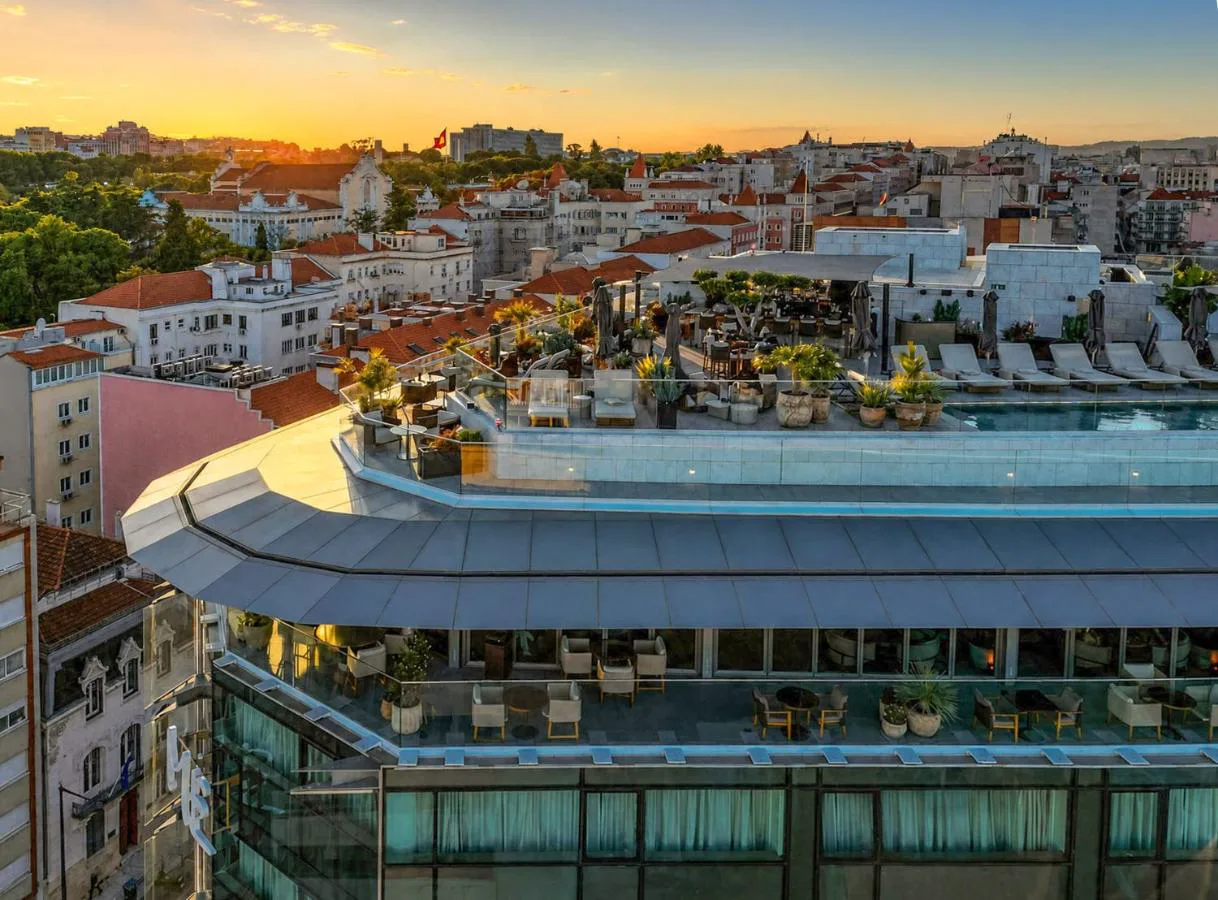 Terraza y piscina en la azotea de ME by Meliá Lisbon al atardecer, con vistas a la ciudad