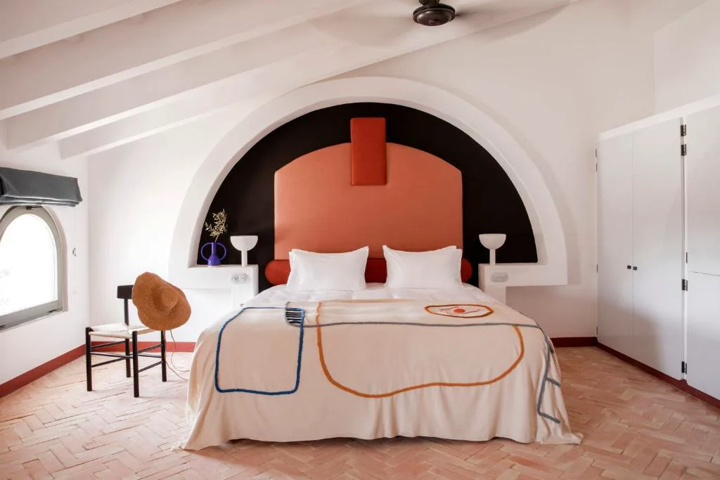 Dormitorio con cabecero abovedado en terracota y suelo de baldosa hidráulica, Menorca Experimental