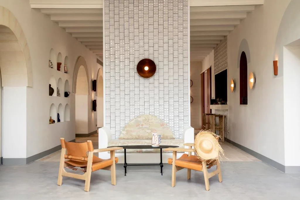 Salón de estar con arcos de piedra, banco tapizado y sillones de cuero, Menorca Experimental