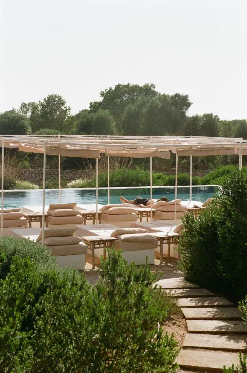 Piscina exterior bajo un porche de tela junto al jardín mediterráneo, Menorca Experimental