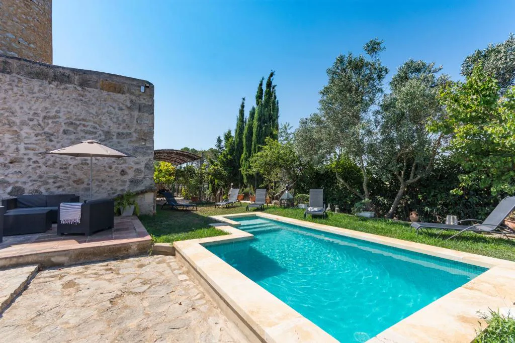 Piscina junto a la torre de piedra de un antiguo molino de viento rehabilitado, Molí D'en Barret, en Santa Margalida, Mallorca