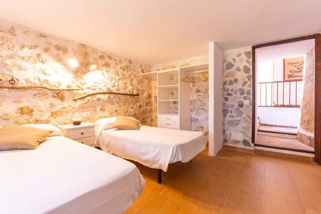 Dormitorio con paredes de piedra vista y balcón de forja, Molí D'en Barret
