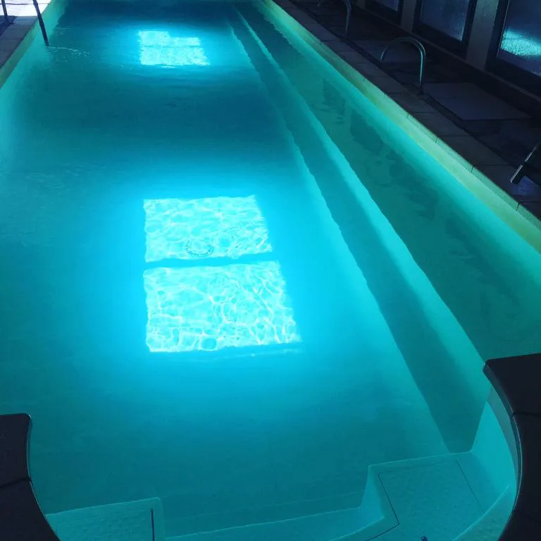 Piscina cubierta alargada con luz turquesa