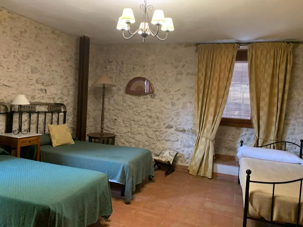Habitación con muro de piedra y camas con colchas verdes