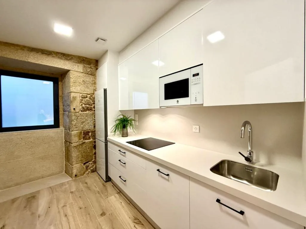 Cocina blanca moderna con ventana enmarcada en piedra, Morada Atlántica