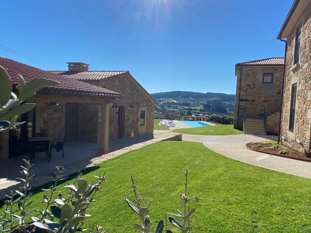 Vista panorámica del conjunto de casas de piedra con la piscina y el valle al fondo